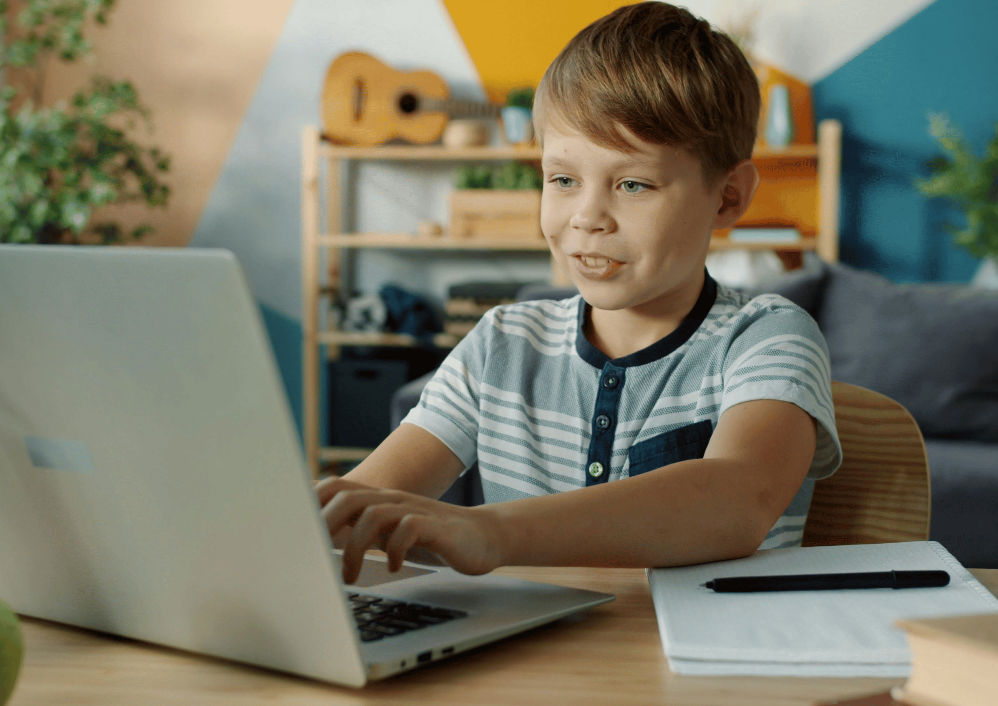 boy on a laptop smiling while typing